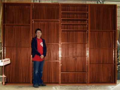 Front view of a set of tall free-standing bookshelves with me standing in front of them for scale