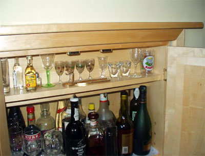 Close up of the corner of a drink cabinet with detail of the door fittings and interior shelves