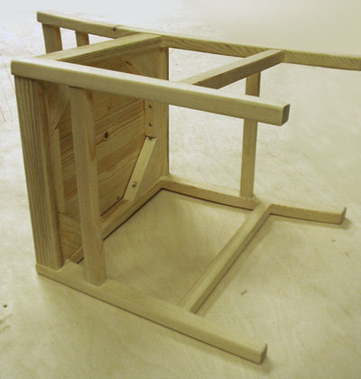 A pale coloured wooden chair lying on its side, viewed from the bottom